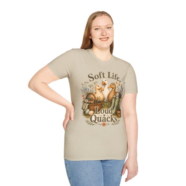 T-Shirt — "Soft Life, Loud Quacks" Cute Duck Graphic Tee one dramatic duck standing in shallow pond water with cattails, ripples, reeds, and a slightly judgmental expression. Give the duck a...