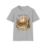 T-Shirt — "Soft Life, Loud Quacks" Cute Duck Graphic Tee one dramatic duck standing in shallow pond water with cattails, ripples, reeds, and a slightly judgmental expression. Give the duck a...