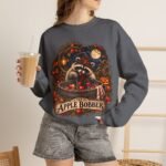 Crewneck Sweatshirt — "The Apple Bobber" Halloween Raccoon Apple-Bobbing Design
