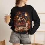 Crewneck Sweatshirt — "The Apple Bobber" Halloween Raccoon Apple-Bobbing Design