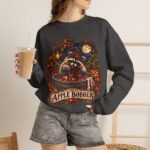 Crewneck Sweatshirt — "The Apple Bobber" Halloween Raccoon Apple-Bobbing Design